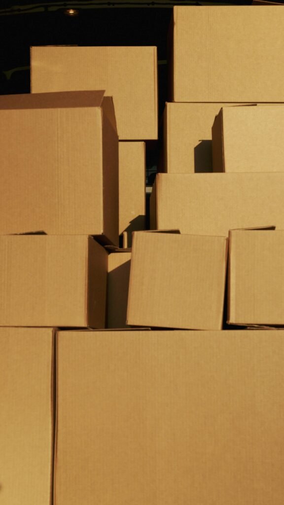 Vertical arrangement of various sized cardboard boxes in warm sunlight, ideal for packaging themes.